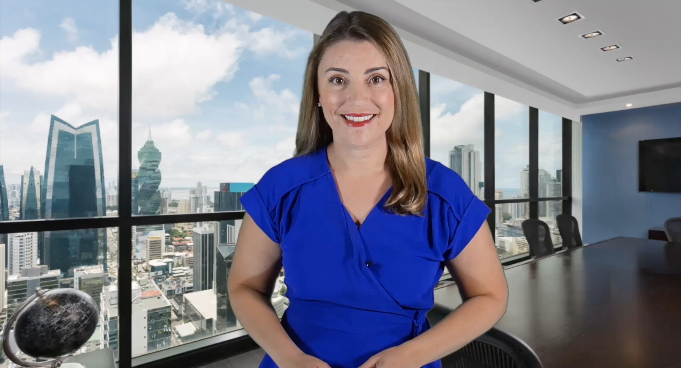 Smiling woman in blue blouse posing in a modern office with city view.