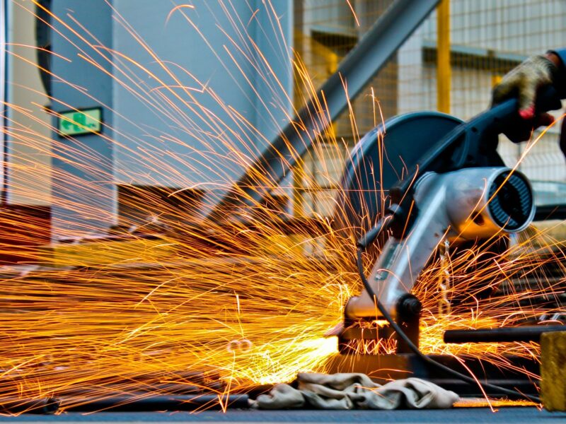 Worker grinding metal, sparks flying brightly.