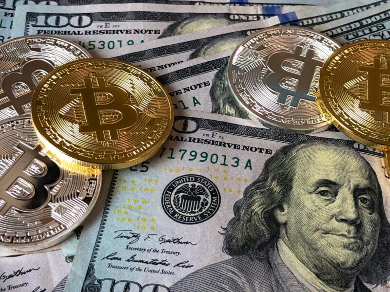 Bitcoin coins on US dollar bills with a glass globe.