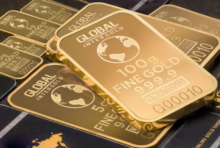 Stack of 100g fine gold bars with global design.