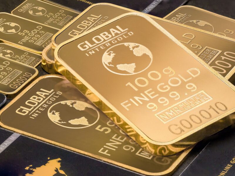 Stack of 100g fine gold bars with global design.