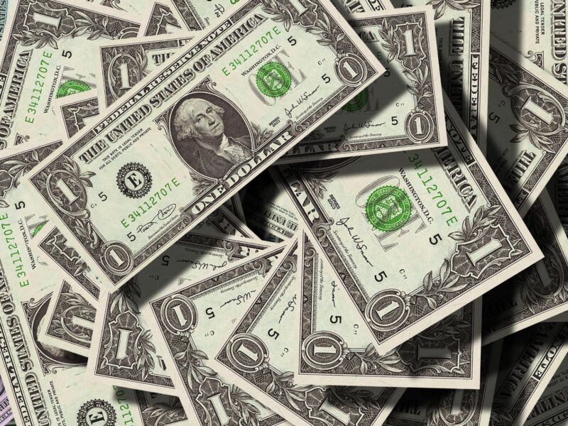 A pile of scattered one-dollar bills.